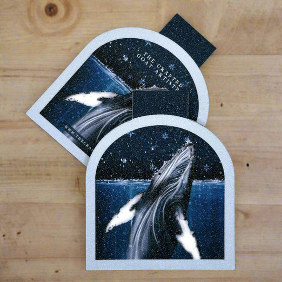 Two arched shaped magnetic bookmarks showing the front and back of Humpback Whale coming out of the water with snowflakes 