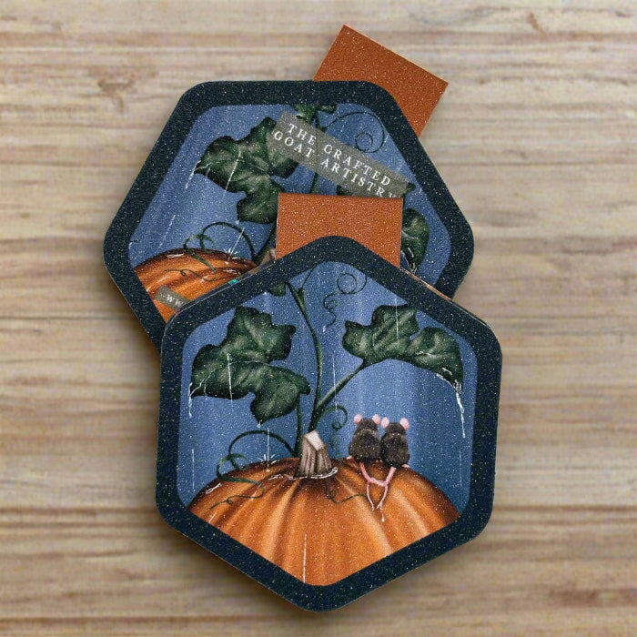 Two hexagon shaped magnetic bookmarks showing the front and back of two mice sitting on an orange pumpkin in the rain